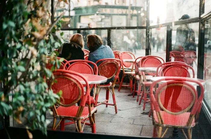 Charming outdoor cafe with vibrant red chairs and cozy atmosphere, ideal for a relaxing city break.