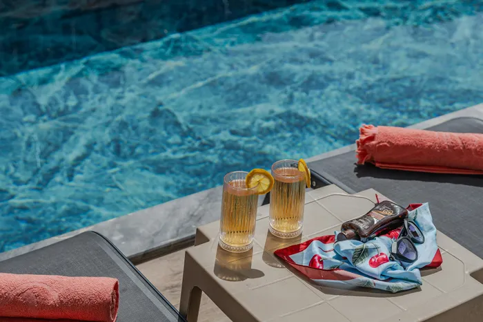 Inviting poolside setup with refreshing drinks, vibrant towels, and stylish sunglasses, perfect for a sunny escape.