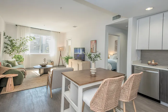 Bright and modern living area with natural light, cozy seating, and stylish dining space adjoining a sleek kitchen.