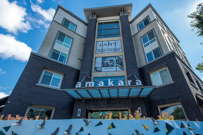 Modern apartment building exterior featuring sleek architectural design, vibrant signage, and lush landscaping, ideal for urban living.