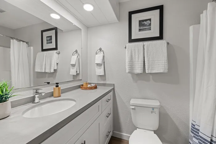Modern bathroom featuring a sleek countertop, elegant white cabinetry, and cozy towel arrangement under soft lighting.