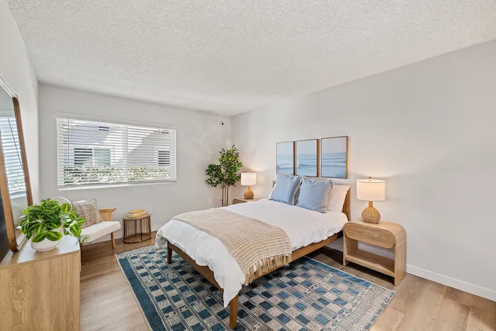 Bright and cozy bedroom with stylish decor, featuring a plush bed, elegant bedside lamps, and vibrant indoor plants.
