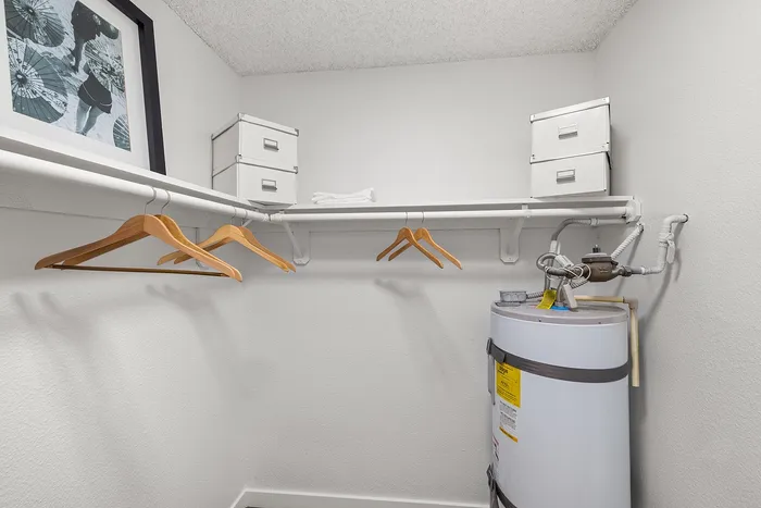 Modern utility closet featuring sleek metal storage boxes, wooden hangers, and a water heater for efficient organization.