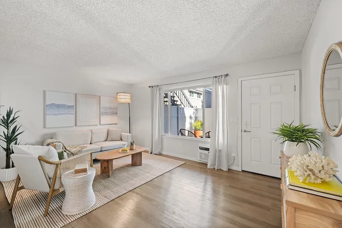 Inviting living room with modern decor, featuring a comfortable sofa, stylish coffee table, and large window allowing natural light to brighten the space.