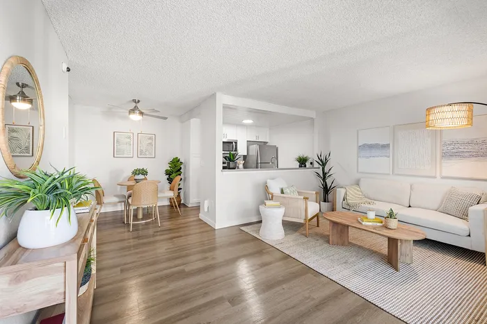 Inviting modern living space with open-concept layout, featuring a cozy living room, stylish dining area, and a sleek kitchen. Accents of green plants add a refreshing touch to the bright and airy ambiance.