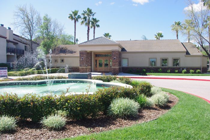 Twin Creeks leasing office exterior with a tiled fountain, palm trees, and manicured landscaping.