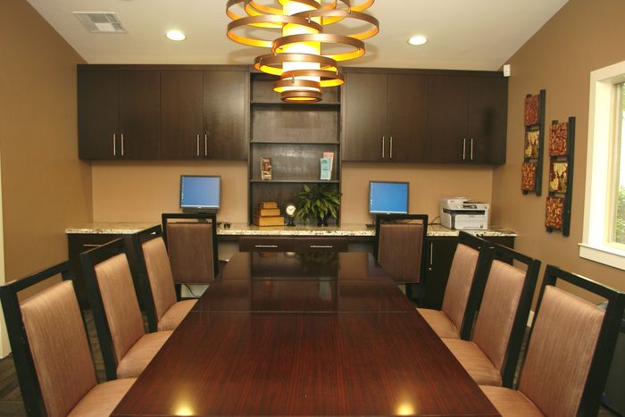 Twin Creeks business center with a long conference table, workstation computers, and printer available for residents.