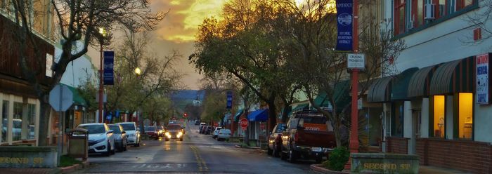 Charming downtown Antioch street at dusk, lined with historic storefronts, parked cars, and mature trees.