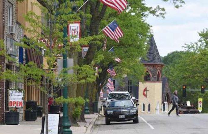 Charming downtown street lined with American flags, storefronts, and a historic church steeple near Antioch.