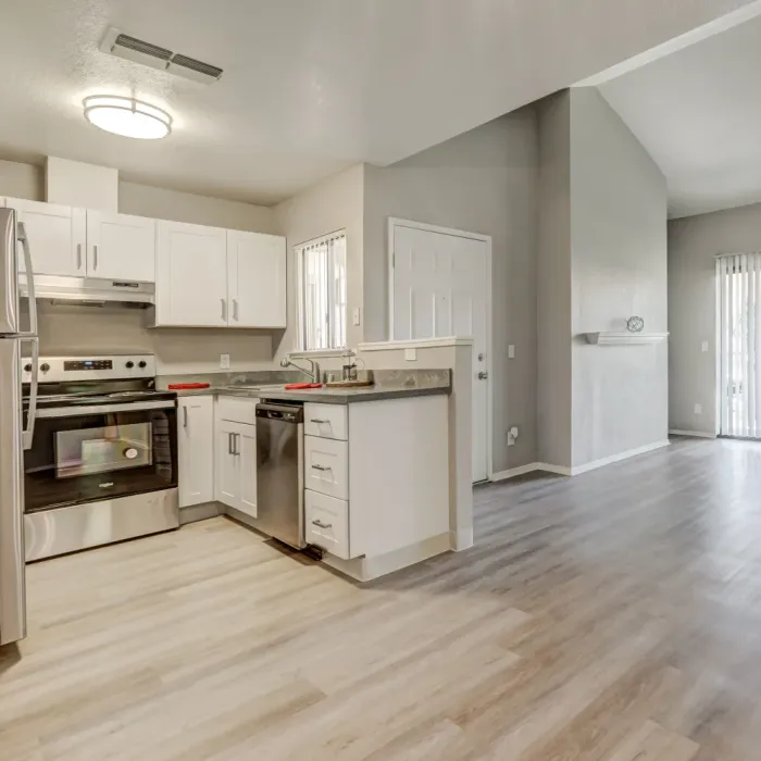 Twin Creeks apartment kitchen with white cabinetry, stainless steel appliances, and an open layout into the living area.