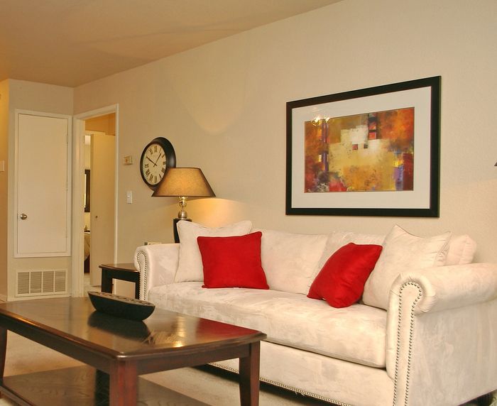 Twin Creeks apartment living room with a cream sofa, framed artwork, and an open view into the dining area.