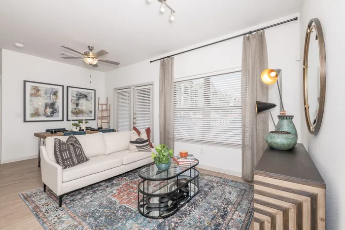 Bright and stylish living room with a modern beige sofa, vibrant patterned rug, and decorative accents, offering a cozy ambiance and elegant design.