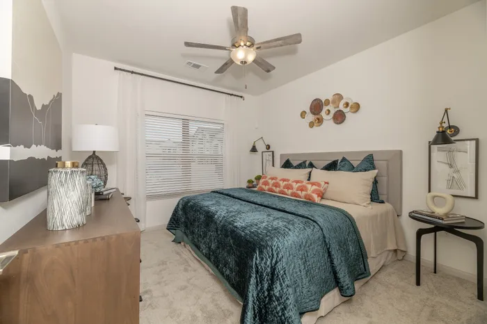 Elegant bedroom featuring a cozy upholstered bed with plush pillows, artistic wall decor, and a modern ceiling fan for ultimate comfort.