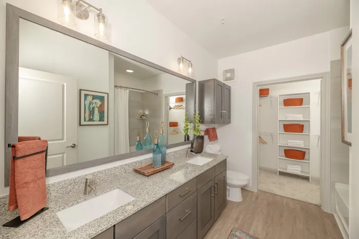 Elegant modern bathroom featuring a granite double vanity, stylish lighting, and ample storage with decorative accents.
