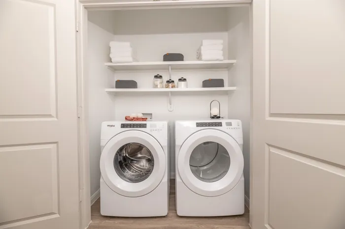Modern laundry room with sleek washer and dryer set, organized shelves, and stylish storage solutions.