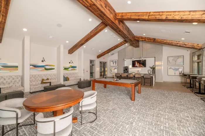 Inviting community lounge with rustic wooden beams, modern seating, and a stylish pool table, perfect for relaxation and social gatherings.