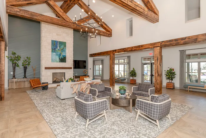 Elegant living room with vaulted ceilings, rustic wooden beams, and a cozy seating area centered around a stone fireplace.