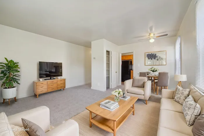 Virtually staged living room with elegant beige seating, wooden coffee table, and flat-screen TV.