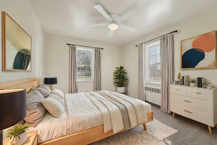 Bright and inviting bedroom featuring a cozy bed, modern decor, and large windows with natural light.