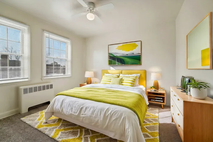 Bright and inviting bedroom featuring a yellow and white color scheme with modern decor and natural light.