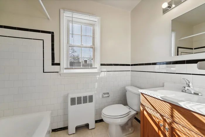 Elegant bathroom with white tiles, modern fixtures, and a window letting in natural light.
