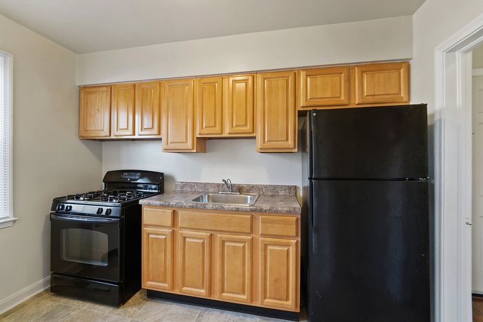 Contemporary kitchen with wooden cabinets, black refrigerator, and gas stove.