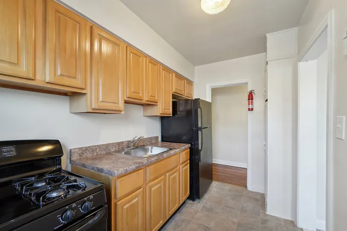 Contemporary kitchen with wooden cabinetry, black appliances, and a compact layout.