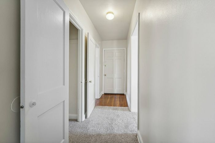 Bright and welcoming hallway with white doors and soft carpet flooring.