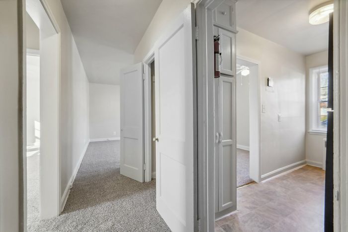 Inviting hallway in a modern apartment with soft carpeting and elegant white doors.