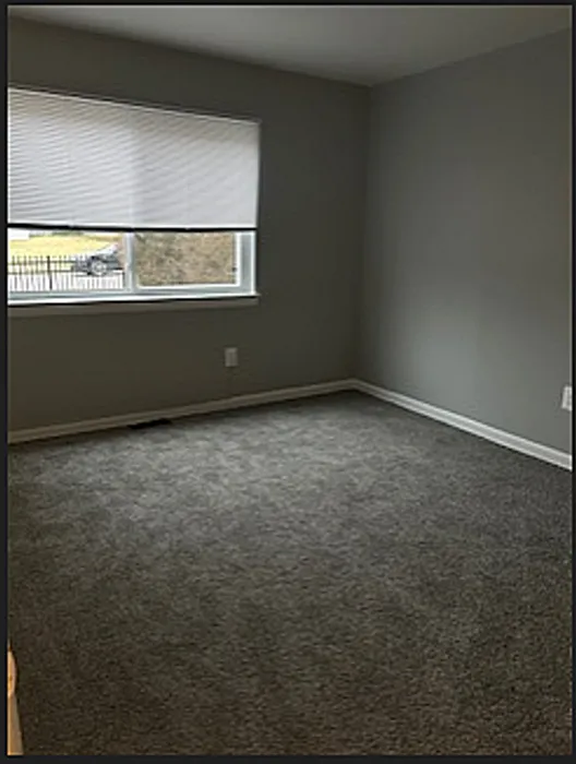 Inviting bedroom with plush carpeting and large window offering natural light.