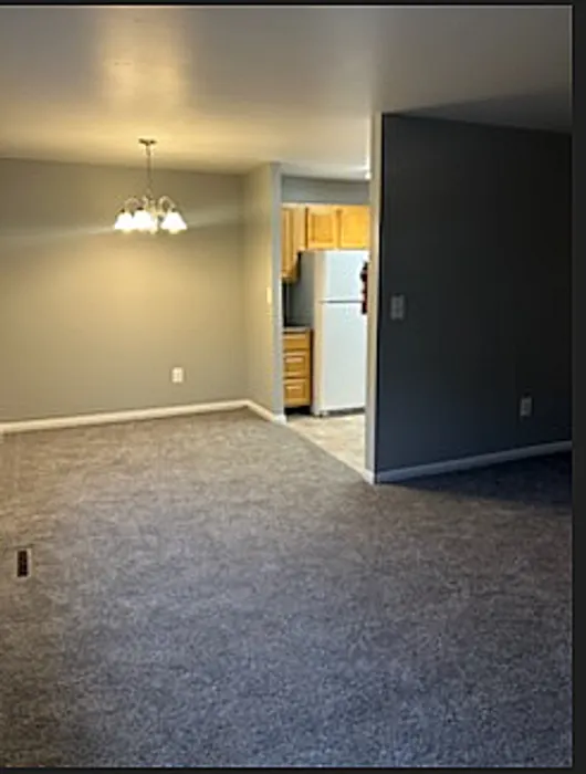Inviting apartment interior with carpeted living area and adjacent open kitchen.