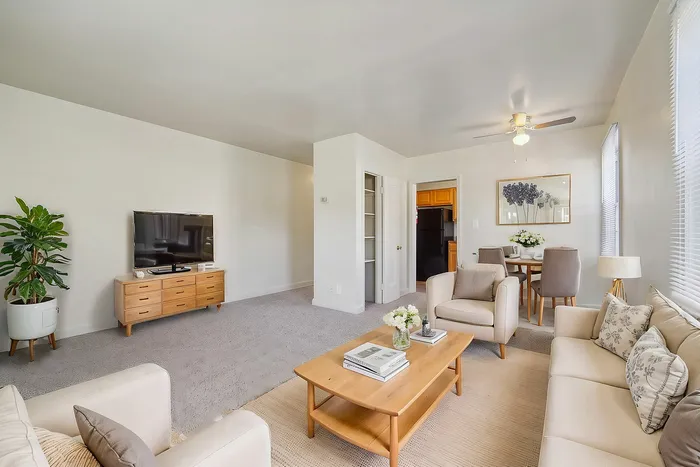 Bright and airy living room with modern furniture, TV, and dining area.