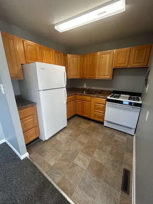 Cozy kitchen featuring wooden cabinets, modern appliances, and tiled flooring for a warm and inviting atmosphere.