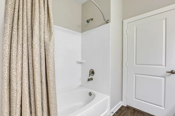 Elegant bathroom featuring a modern bathtub with a sleek shower fixture and stylish, patterned shower curtain.