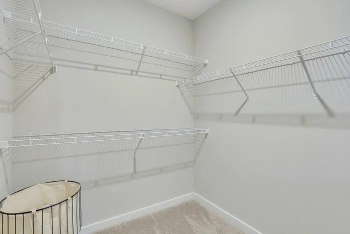 Spacious walk-in closet with sleek white wire shelving, perfect for organized storage solutions.