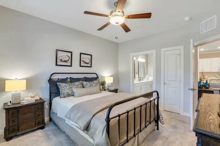 Inviting bedroom with elegant decor, featuring a plush bed under a stylish ceiling fan, cozy bedside tables, and a glimpse of the modern ensuite bathroom.
