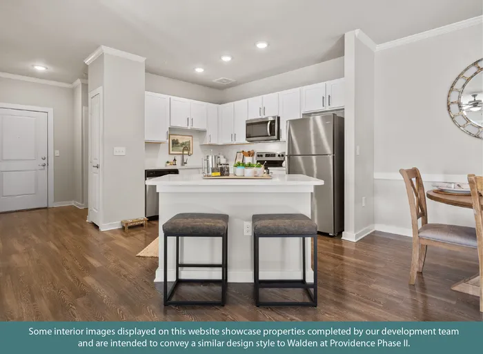 Contemporary kitchen with sleek stainless steel appliances, elegant white cabinetry, and a cozy breakfast bar with stylish stools, perfect for modern living.