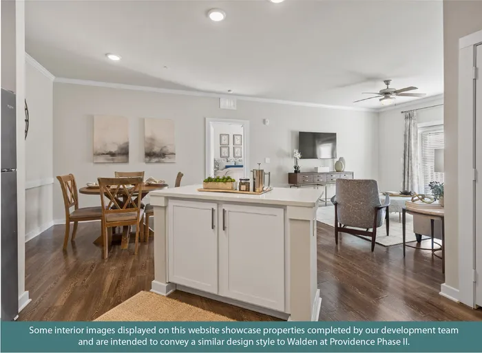 Modern open-plan living space featuring a sleek kitchen island, cozy dining area, and stylish living room with warm hardwood floors and elegant decor.