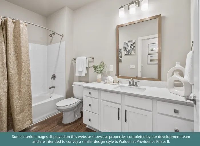 Elegant bathroom featuring a modern vanity with a large mirror, chic lighting, and a stylish shower curtain in a serene, well-lit setting.