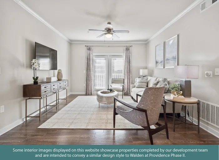 Chic living room with modern decor, featuring a sleek media console, comfortable seating, and a stylish ceiling fan, bathed in natural light from large windows.