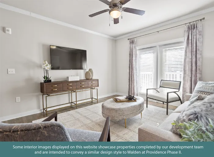 Bright and elegant living room featuring modern decor, large windows with sheer curtains, plush seating, and a sleek TV stand.