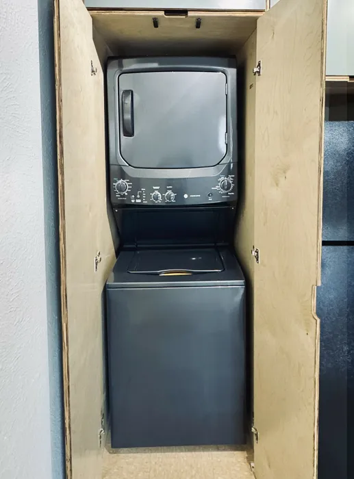 Efficient stacked washer and dryer set in a sleek wooden closet, offering convenient in-home laundry solutions.