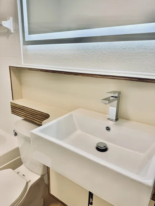 Elegant bathroom with a modern sink, sleek faucet, and illuminated mirror offering contemporary style and functionality.