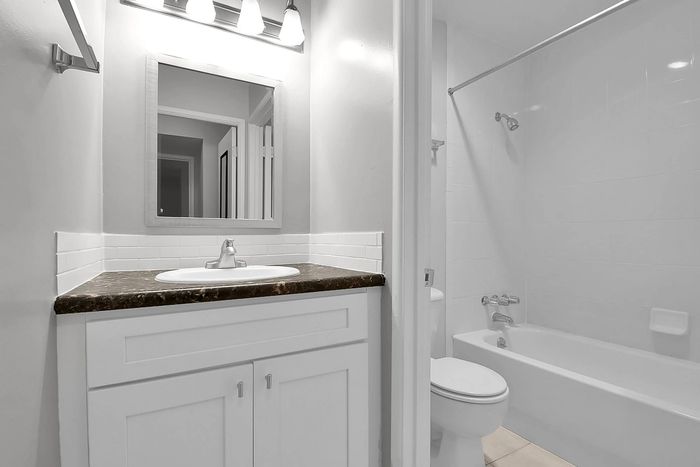 Modern bathroom with sleek fixtures, elegant white cabinetry, and a spacious bathtub.
