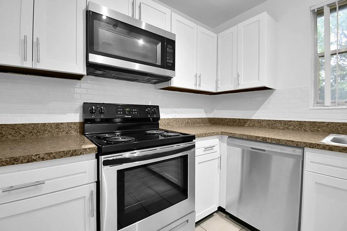 Modern kitchen with sleek stainless steel appliances, elegant white cabinetry, and polished granite countertops.