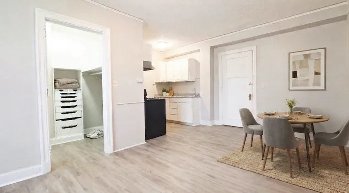 Modern apartment interior featuring sleek kitchen, cozy dining area with elegant four-seat table, and a spacious closet.