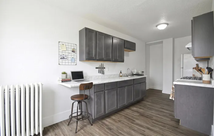Modern kitchen with sleek gray cabinets, marble countertops, and a cozy breakfast nook, perfect for a stylish lifestyle.