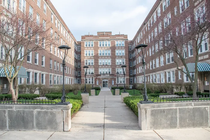 Charming brick apartment complex with a landscaped courtyard, featuring elegant architecture and inviting green spaces.