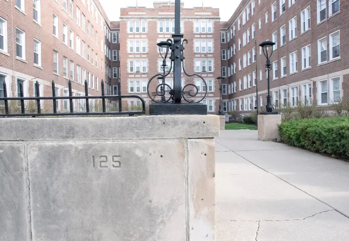 Charming brick apartment building with vintage architectural features and well-maintained landscaping, offering a welcoming residential atmosphere.