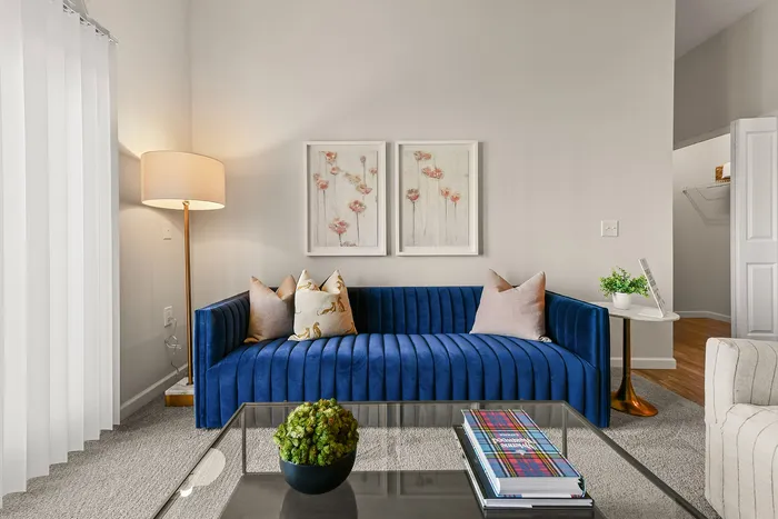 Chic living room with a plush blue velvet sofa, stylish d&eacute;cor, and bright art pieces creating a welcoming ambiance.